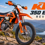 Orange KTM 350 EXC-F enduro motorcycle parked on a rocky mountain trail during sunset.
